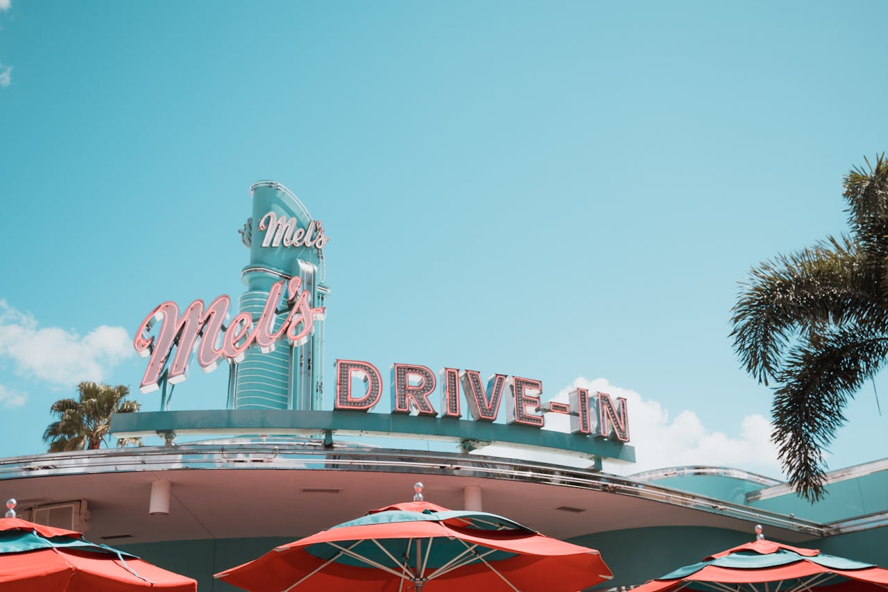 team-03 A vintage drive-in diner featuring classic neon signage and vibrant red umbrellas.